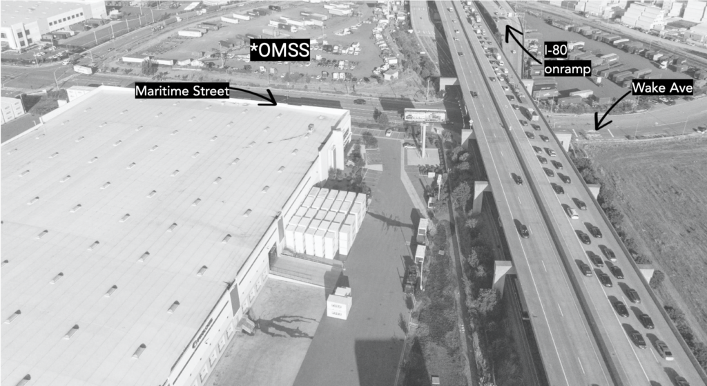 Black-and-white aerial photo of I-80 running top to bottom and Maritime Street running from the left underneath I-80 into Wake Street to the right.